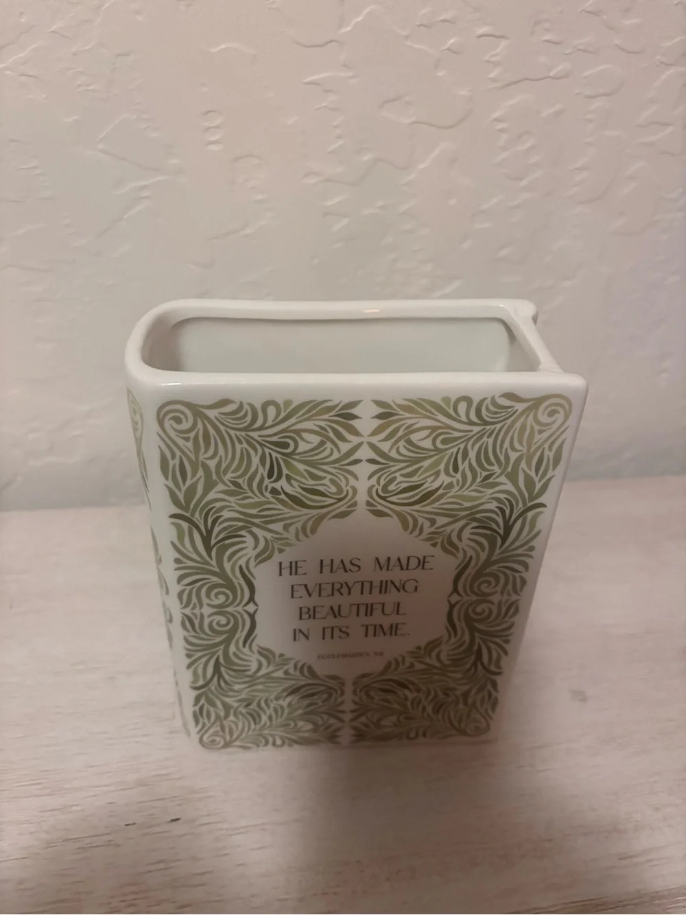 ceramic book vase with green floral swirls and the words…